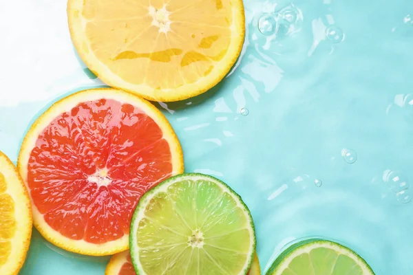 Turkuaz arka planda sudaki narenciye dilimleri, düzlük.