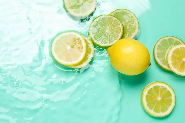 Turkuaz arka planda sudaki narenciye dilimleri, düzlük.