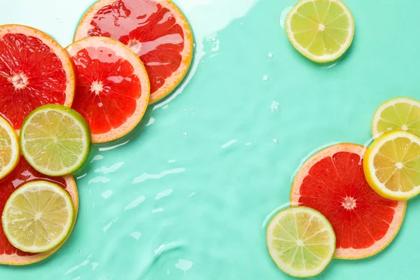 Turkuaz arka planda sudaki turunçgil meyveleri, düzlük. Metin için boşluk