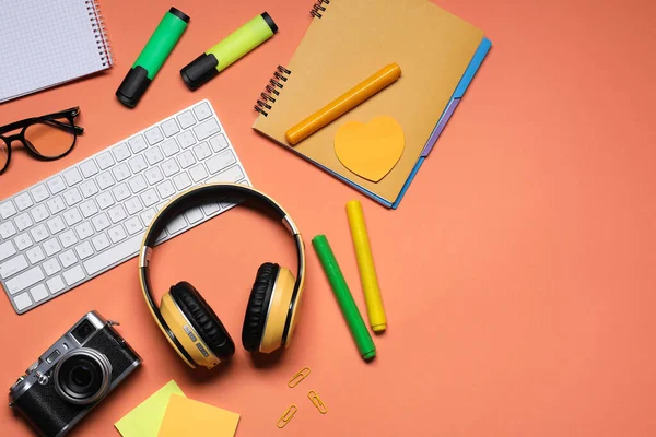 Kulaklıklar, bilgisayar klavyesi, klasik kamera, mercan arka planda gözlük ve kırtasiye malzemesi, düz konum. Metin için boşluk