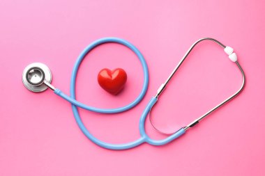 Pembe arka planda steteskop ve kırmızı kalp, düz yatıyordu.