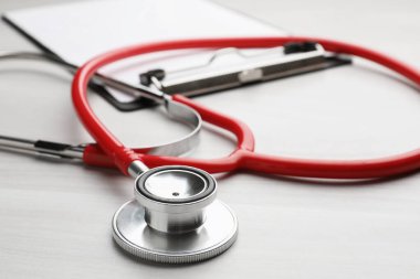 Kırmızı steteskop ve pano açık ahşap masada, yakın plan.
