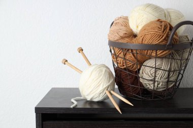 Beyaz duvarın yanındaki siyah ahşap şifoniyere iplikler ve iğneler. Metin için boşluk