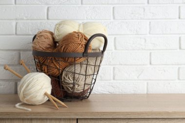 Beyaz tuğla duvarın yanındaki ahşap masada iplikler ve iğneler var. Metin için boşluk