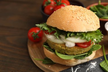 Tahta masada servis edilen vejetaryen köfteli ve sebzeli lezzetli burger. Metin için boşluk