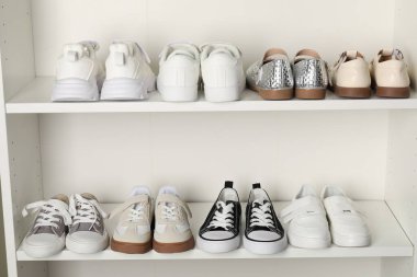 Raf ünitesinde farklı stil çocuk ayakkabıları var. Kapalı, yakın çekim.