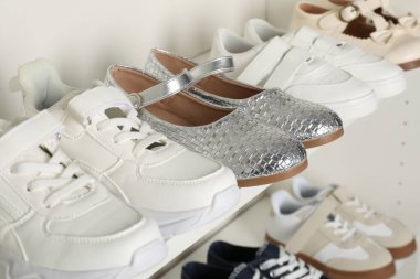 Raf ünitesinde farklı stil çocuk ayakkabıları var. Kapalı, yakın çekim.