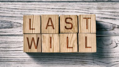 Son vasiyet. Tahta masanın üstünde harflerle yazılmış küplerden yapılmış kelimeler. Pankart tasarımı