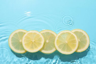 Açık mavi arka planda limon dilimleri, düz. Metin için boşluk