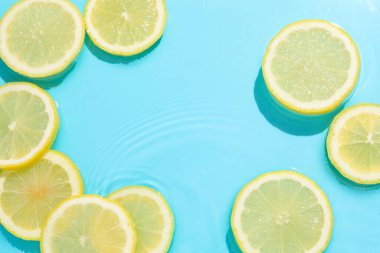 Açık mavi arka planda limon dilimleri, düz. Metin için boşluk
