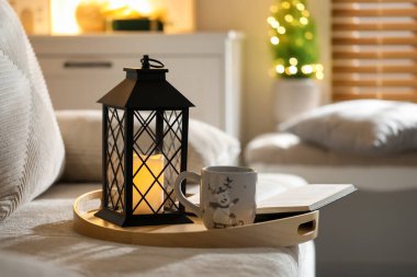 Güzel Noel feneri, bir fincan sıcak içecek ve evdeki kanepede kitap.