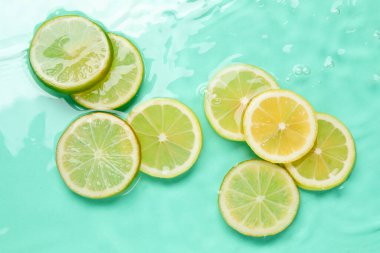 Turkuaz arka planda sudaki narenciye dilimleri, düzlük.