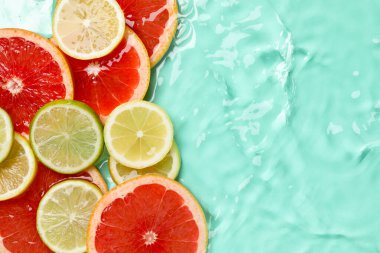 Turkuaz arka planda sudaki turunçgil meyveleri, düzlük. Metin için boşluk