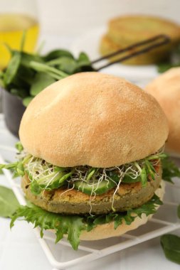 Vejetaryen köfteli lezzetli hamburger ve sebzeler beyaz fayanslı masada servis edilir, yakın plan.