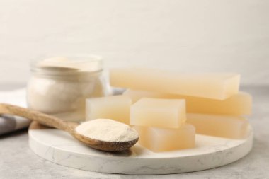 Jelatin tozu ve jöle parçaları gri masada, yakın plan.