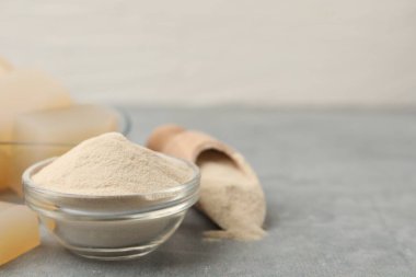 Jelatin tozu ve jöle küpleri gri masada, yakın plan. Metin için boşluk