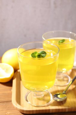 Tatlı kaselerinde leziz sarı jöle, nane ve taze limon ahşap masada, yakın plan.