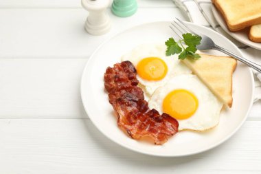Beyaz ahşap masada servis edilen yağda yumurta ve pastırmalı nefis bir kahvaltı.