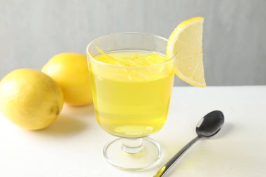 Tatlı kasesinde leziz sarı jöle ve beyaz masada limonlar, yakın plan.