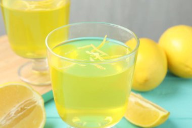 Tatlı kaselerinde leziz sarı jöle ve açık mavi ahşap masada limonlar, yakın plan.