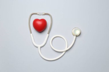 Kan basıncını ölçüyorum. Açık gri arka planda steteskop ve kalp figürü, üst görünüm