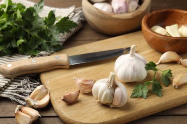 Taze sarımsak soğanları, karanfiller, maydanoz ve bıçak ahşap masada, yakın plan.