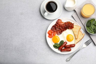 Açık gri masada servis edilen kızarmış yumurta, sosis ve domuz pastırması ile nefis bir kahvaltı. Metin için boşluk