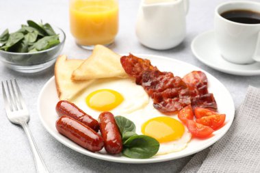 Açık gri masada servis edilen yağda yumurta, sosis ve pastırma ile nefis bir kahvaltı.