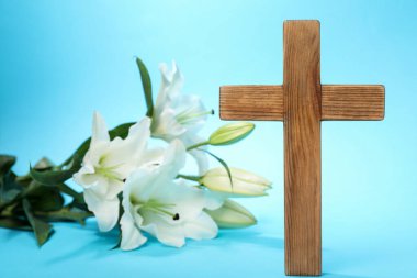 Paskalya. Ahşap haç ve güzel zambak buketi açık mavi arka planda, yakın plan