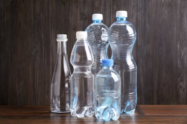 Tahta masada farklı boyutlarda su şişeleri var.