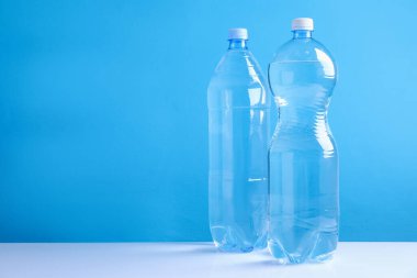 Açık mavi arkaplana karşı beyaz masada temiz su şişeleri, metin için boşluk