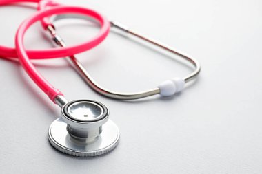 Açık gri arkaplanda pembe steteskop, yakın plan.