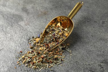 Gri masada kurumuş yeşil çay yaprakları ve metal spatula, yakın plan.