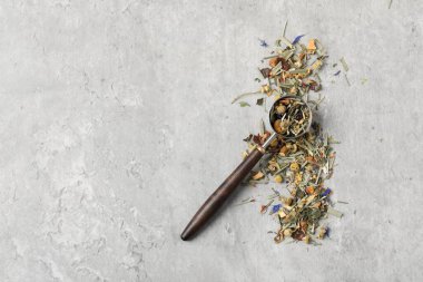 Açık gri masada kurutulmuş bitki çayı ve ölçü kaşığı, üst manzara. Metin için boşluk