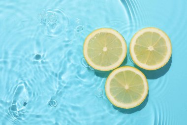 Açık mavi arka planda limon dilimleri, düz. Metin için boşluk