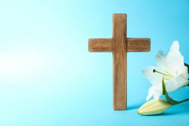 Paskalya. Ahşap haç ve açık mavi arkaplanda güzel zambak çiçekleri, metin için yere yakın çekim