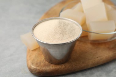 Kasede jelatin tozu ve gri masada jöle küpleri, yakın plan.