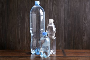 Tahta masada farklı boyutlarda su şişeleri var.