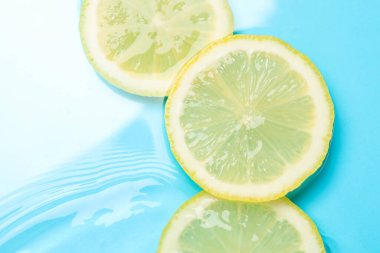 Açık mavi arka planda limon dilimleri, düz. Metin için boşluk