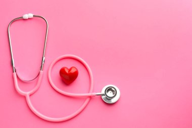 Pembe arka planda steteskop ve kırmızı kalp. Metin için boşluk