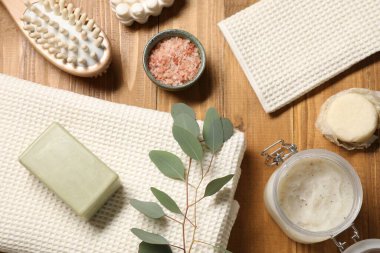 Temiz waffle havluları, kişisel bakım ürünleri ve okaliptüs dalı ahşap masa, düz uzanma