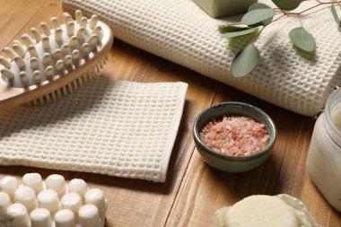 Temiz waffle havluları, kişisel bakım ürünleri ve okaliptüs yaprakları ahşap masada, yakın plan.