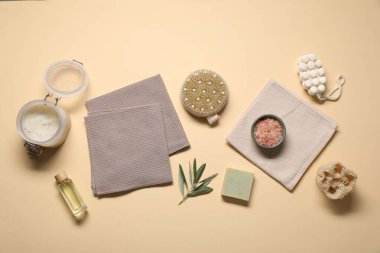 Bej arka planda waffle havluları ve kişisel bakım ürünleriyle düz konum