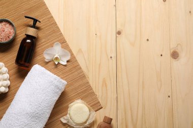 Temiz havlu, kozmetik ürünler ve orkide. Tahta masa, düz yatak. Metin için boşluk