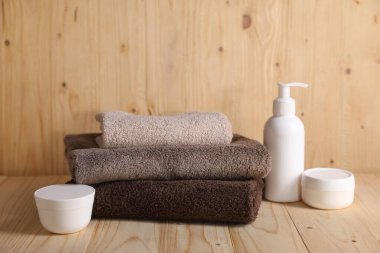 Ahşap masada temiz havlular ve kozmetik ürünler.