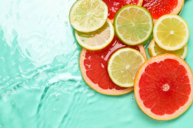 Turkuaz arka planda sudaki turunçgil meyveleri, düzlük. Metin için boşluk