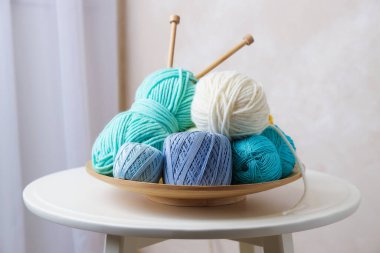 Beyaz sehpanın üzerinde örgü iğneleri ve iplikler, yakın plan.