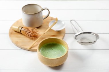 Seramik kasede taze yeşil kibrit, bambu çırpı, kepçe, bardak ve elek beyaz ahşap masa, yakın çekim