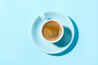 Açık mavi arka planda bir fincan aromatik kahve.
