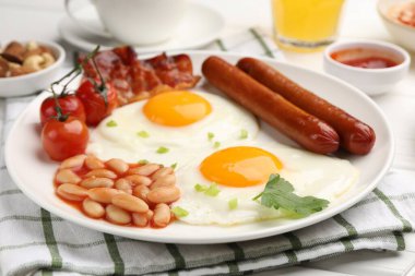 Geleneksel İngiliz kahvaltısı. Lezzetli, güneşli, domuz pastırmalı ve sosisli yumurta, yakın plan.